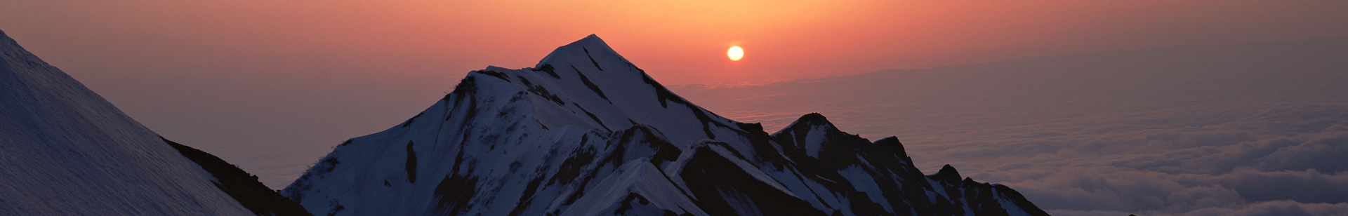 Mountain with the sun peaking through the clouds.