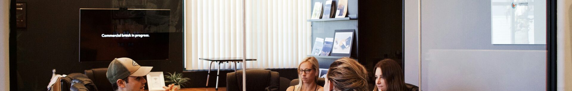 Image of people sitting round a table in a glass doored office | integration HCM