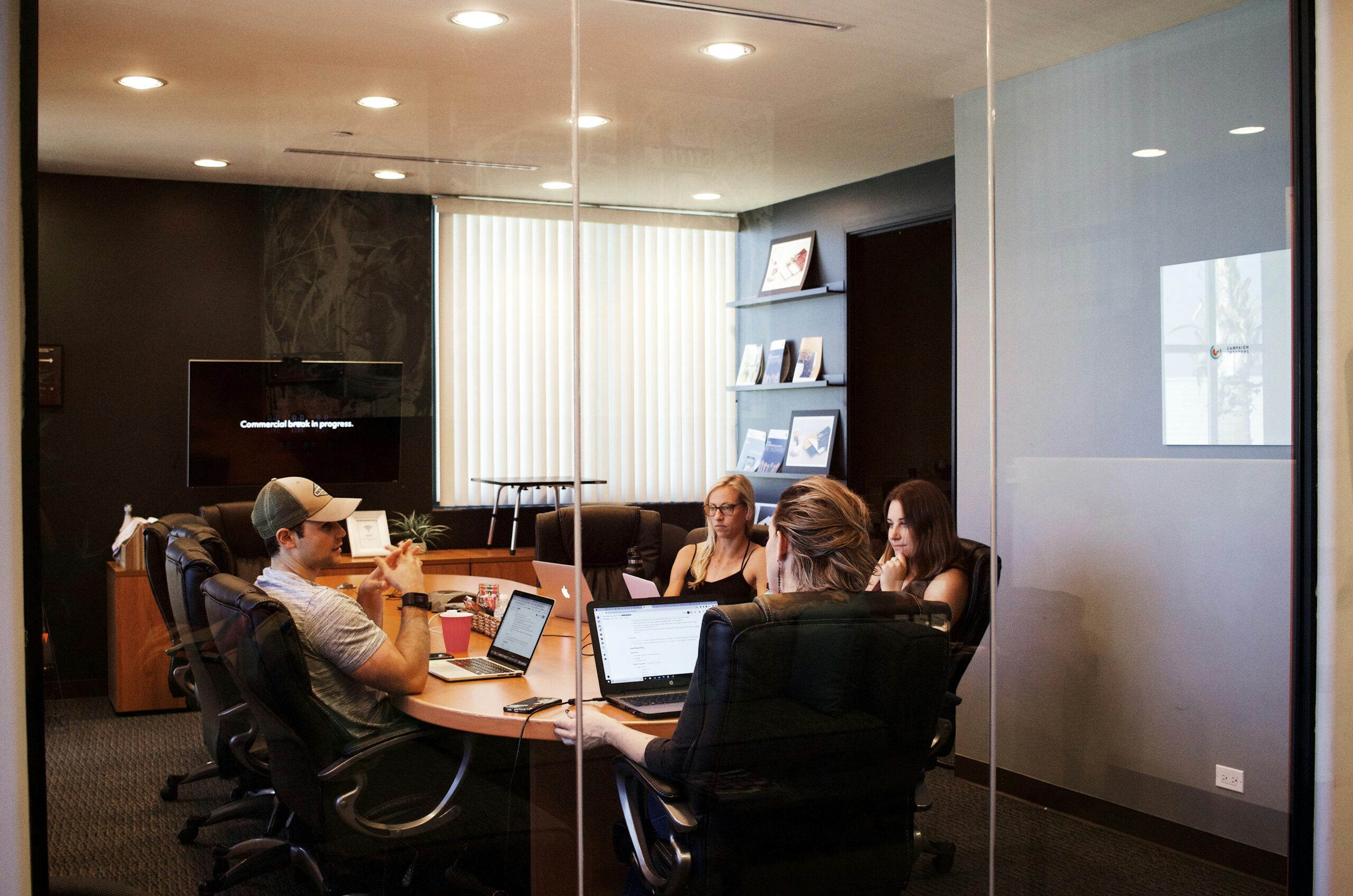 Image of people sitting round a table in a glass doored office | integration HCM