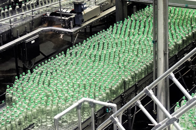 Hundreds of glass bottles with green caps moving along automated conveyor lines in a beverage bottling plant, representing the manufacturing operations behind Suntory Oceania's SAP S/4HANA transformation.